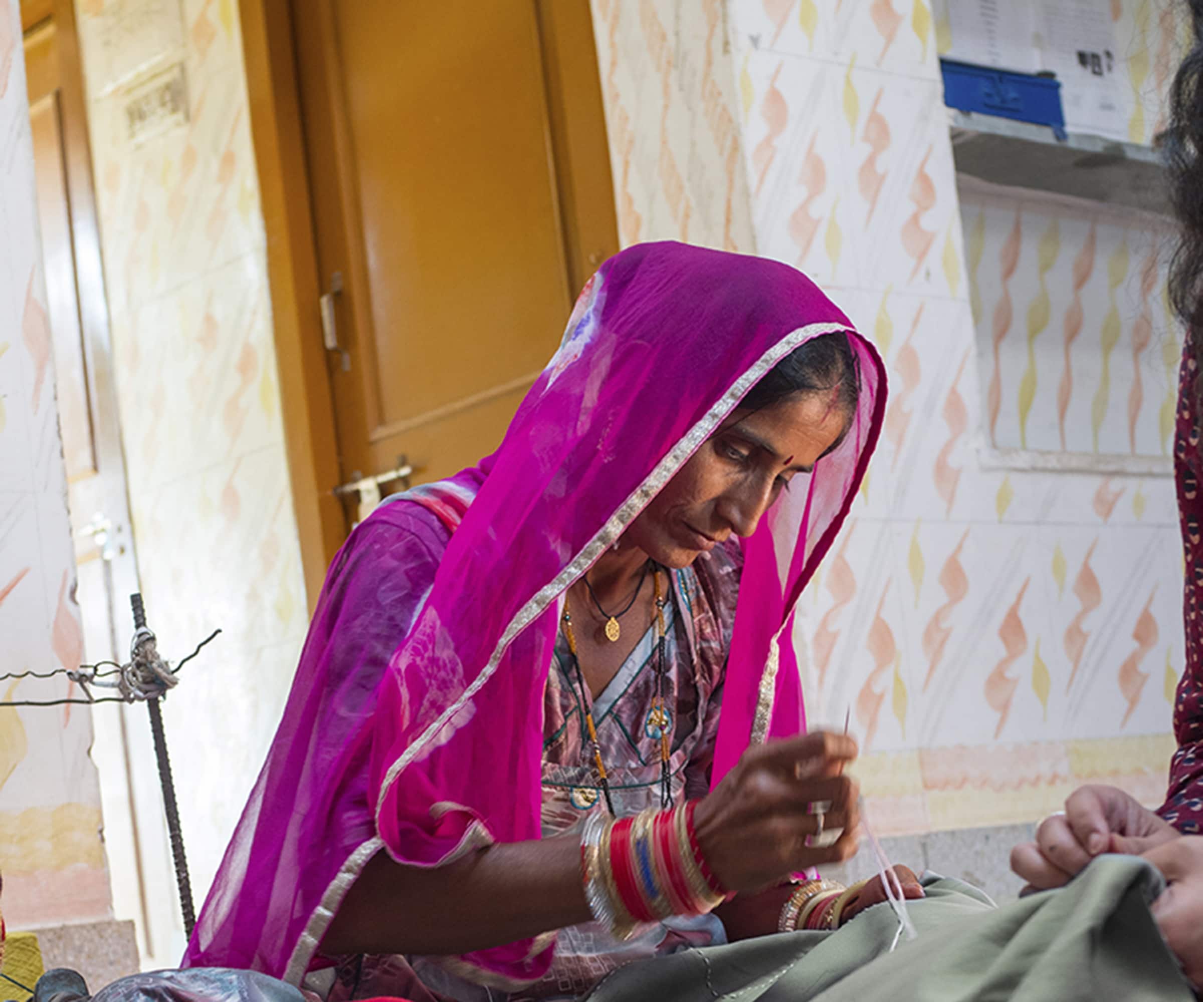 Craftswoman Sahji adding embroidered details to a soon-to-be cushion cover.